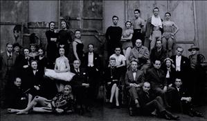 Thirty people, some in ballet costumes, pose for the camera in front of a theater backdrop.